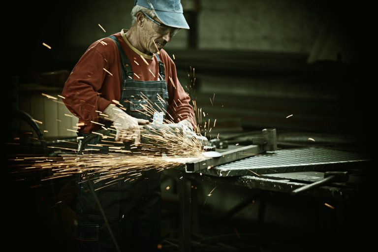 Industrial worker cutting and welding metal with many sharp sparks
